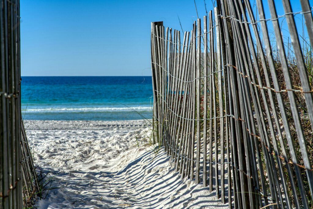 a beach with a fence and a beach in the background